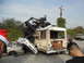 1986 Ford Bronco - A chaotic scene unfolds as a buggy is precariously balanced atop a bus, with crushed cars below.