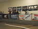1986 Ford Bronco - Spectators watch a race from a viewing area adorned with various sponsor banners.