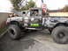1986 Ford Bronco - This heavily modified Toyota pickup truck features oversized tires and numerous decals, with its hood open for engine work.
