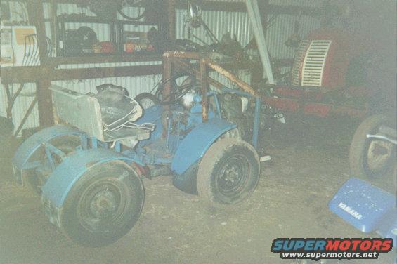 Blue tractor with a roll cage and a red tractor in the background