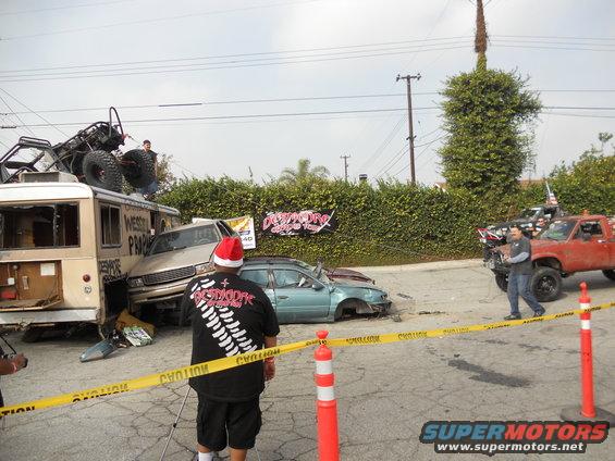 Scene of multiple wrecked vehicles, including a bus and cars, with a custom buggy on top of the bus
