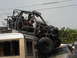 1986 Ford Bronco - Custom off-road buggy is precariously balanced on a van, with another vehicle underneath.