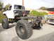 1986 Ford Bronco - This modified pickup truck chassis features massive off-road tires and a rear-mounted toolbox, suggesting custom modifications.
