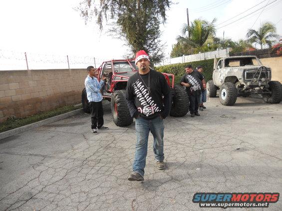 guy in santa hat next to red buggy, another modified truck behind him