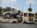 1986 Ford Bronco - A chaotic scene shows a heavily modified pickup truck perched atop other vehicles, with an American flag attached to its rear.