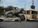 1986 Ford Bronco - A chaotic scene with multiple vehicles in disarray, including a crushed car and a truck precariously balanced.