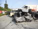 1986 Ford Bronco - A white pickup truck is positioned on top of several crushed cars, with other vehicles visible in the background.
