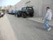 1986 Ford Bronco - A line of modified off-road vehicles is parked outside a commercial building.