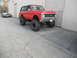 1986 Ford Bronco - This lifted SUV has a custom banner and is parked next to a trailer with another vehicle.