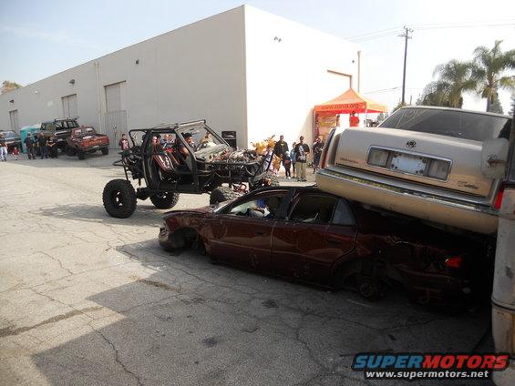 Custom buggy crushing a sedan, topped by a Cadillac