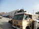 1986 Ford Bronco - A heavily modified RV, possibly a former school bus, is seen with a roll cage and spare tire mounted on its roof, alongside other vehicles.