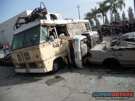 Wrecked bus, overturned car, and sedan piled up after an accident. Text on bus reads '626 9625'