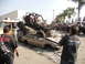 1986 Ford Bronco - An off-road buggy is precariously balanced on a pile of wrecked vehicles, drawing a crowd of onlookers.