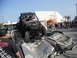 1986 Ford Bronco - An off-road buggy is positioned on top of a severely damaged car, with spectators gathered around.