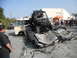 1986 Ford Bronco - A chaotic scene with an off-road buggy perched atop severely damaged cars, a van nearby, and onlookers observing.