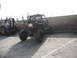1986 Ford Bronco - A custom-built buggy with a prominent roll cage and oversized tires is parked outdoors next to a forklift.