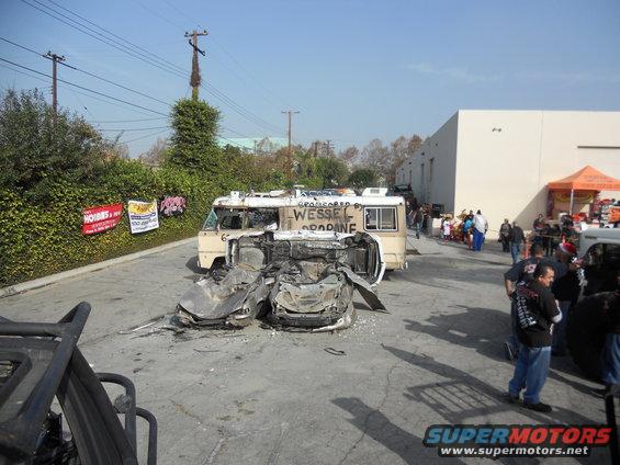 Wrecked car upside down in front of a damaged RV with text 'WESSEL PROPANE' on its side. People are gathered around
