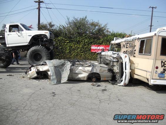 Wrecked car between monster truck and bus with graffiti