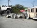 1986 Ford Bronco - A scene of destruction shows a crushed car caught between a monster truck and a graffiti-covered bus.
