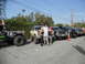 1986 Ford Bronco - Several modified off-road vehicles are parked in a lot, with a group of people standing in front of them.