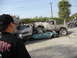 1986 Ford Bronco - A heavily modified pickup truck is parked on top of two wrecked cars, with a person filming the scene.