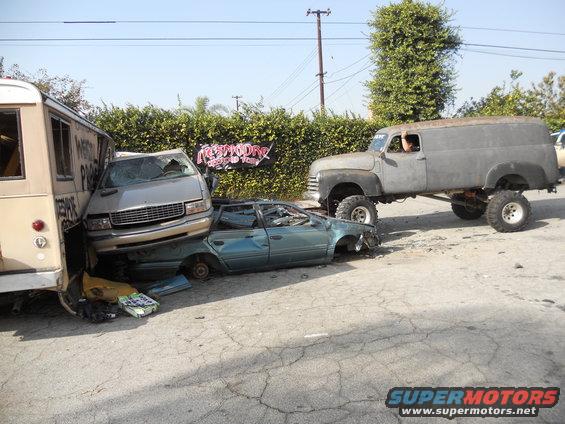 wrecked van, sedan, and bus next to a lifted panel truck