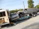 1986 Ford Bronco - A collection of damaged vehicles and a heavily modified panel van are piled up on a street.