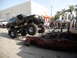 1986 Ford Bronco - A heavily modified black Ford Bronco is shown crushing a red car, with a crowd watching.