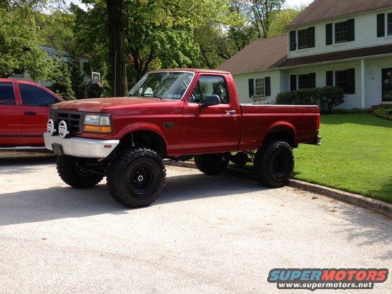 Red 1996 Ford F-150 pickup truck with lifted suspension and large tires