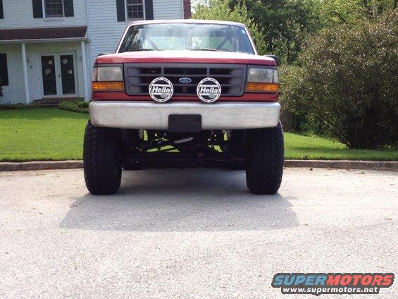 Front view of a red lifted pickup truck with Hella lights on the bumper