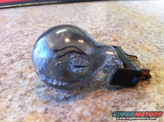 Used light bulb with blackened glass and metal contacts on a speckled countertop