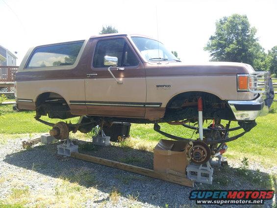 Two-tone brown 1987 Ford Bronco on jack stands with suspension removed