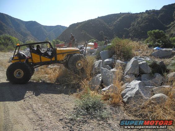 Yellow off-road buggy climbing over rocks on a dirt path