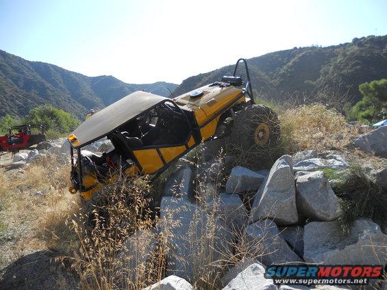 Yellow off-road buggy with roll cage navigating rocky terrain