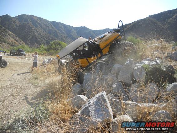 yellow buggy stuck on rocks, person filming