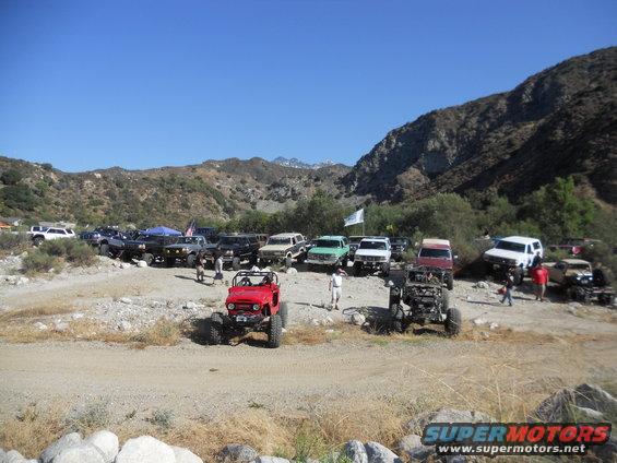 Red off-road buggy in foreground with many SUVs and trucks in background