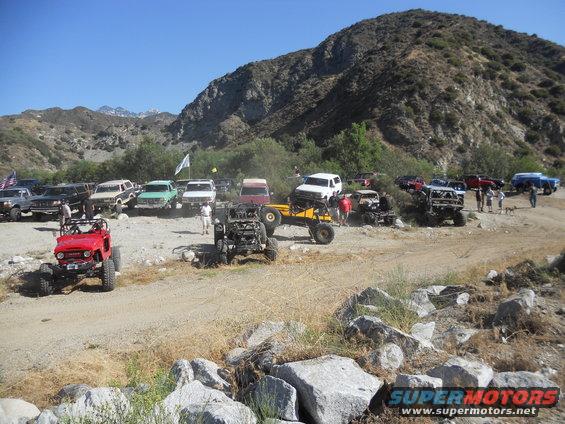 Group of off-road vehicles parked on a dirt road with a mountain in the background
