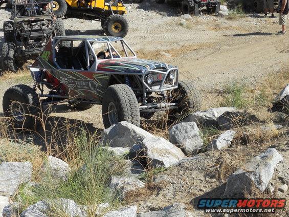 Custom off-road buggy with roll cage navigating rocky terrain