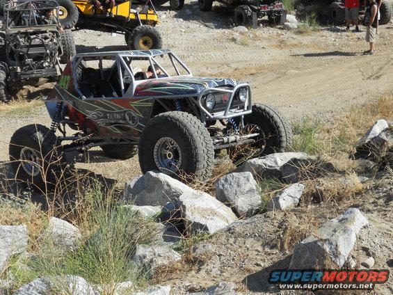 Custom off-road buggy with roll cage navigating rocky terrain