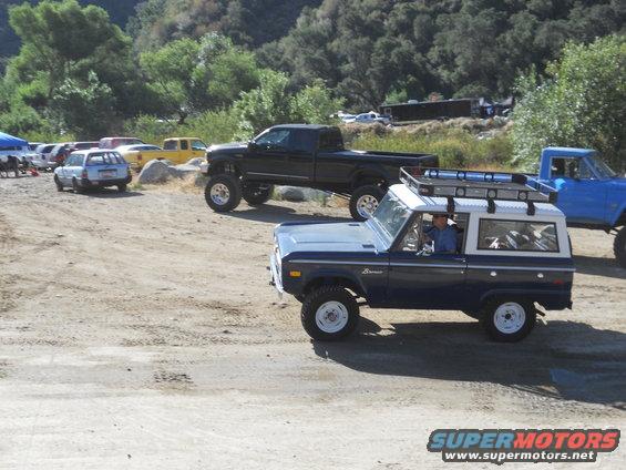 Dark blue Ford Bronco with white roof and roof rack, seen from the front-right