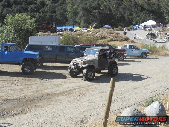 Tan Toyota Land Cruiser FJ40 with roll cage and large tires parked on dirt