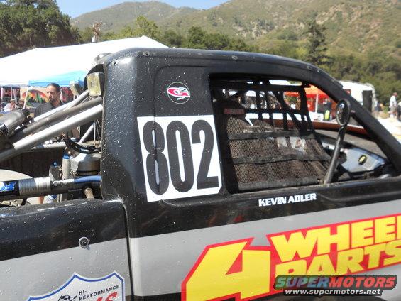 Off-road race truck with number 802 and '4 WHEEL PARTS' livery. Kevin Adler is listed as driver