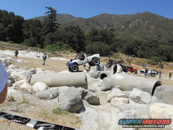 White pickup truck navigating rocky terrain and concrete pipes