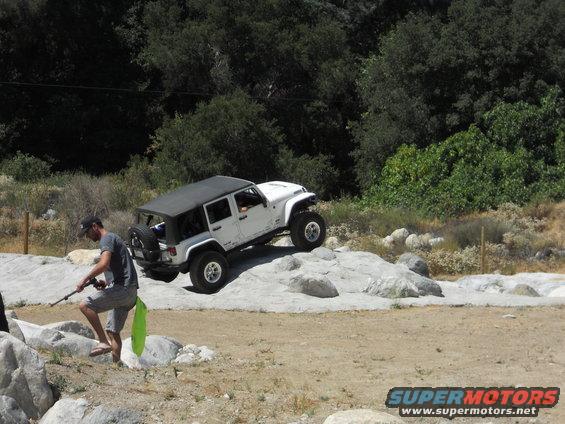 White Jeep Wrangler climbing over rocks on a dirt trail