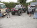 1986 Ford Bronco - A heavily modified pickup truck with large off-road tires and custom roll cage is parked outdoors with other vehicles.