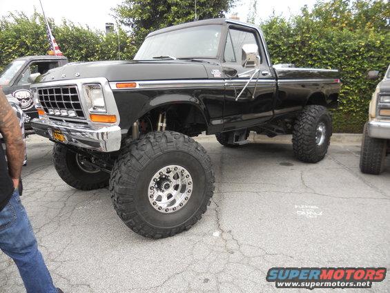 Black lifted Ford pickup truck with chrome grille and large off-road tires, parked on asphalt