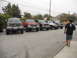 1986 Ford Bronco - A group of modified trucks and SUVs are lined up in a parking lot under an overcast sky.