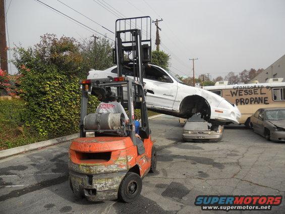 White car lifted by forklift over another car, with "Wessel Propane" text visible