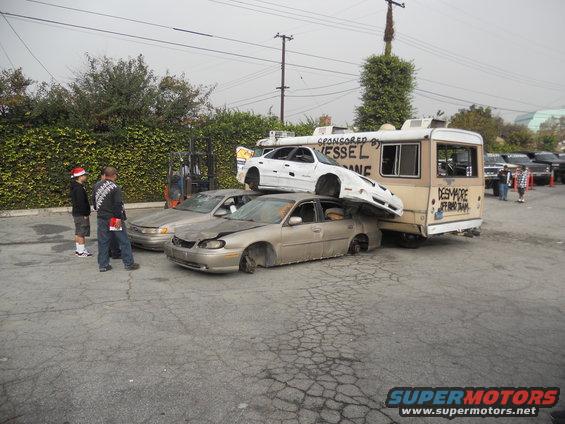 Cars stacked on a bus with text 'DESMORE JEFFRO TEAM' and 'SPONSORED BY VESSEL LANE'