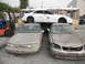 1986 Ford Bronco - A damaged gold Ford Taurus sits in a junkyard next to other vehicles.